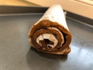 Photo of the Pumpkin Roll cake rolled in the parchment paper waiting to cool