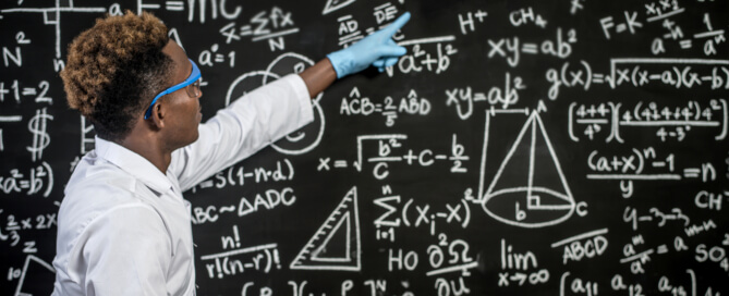 Scientists wear glasses and point to formulas on the blackboard